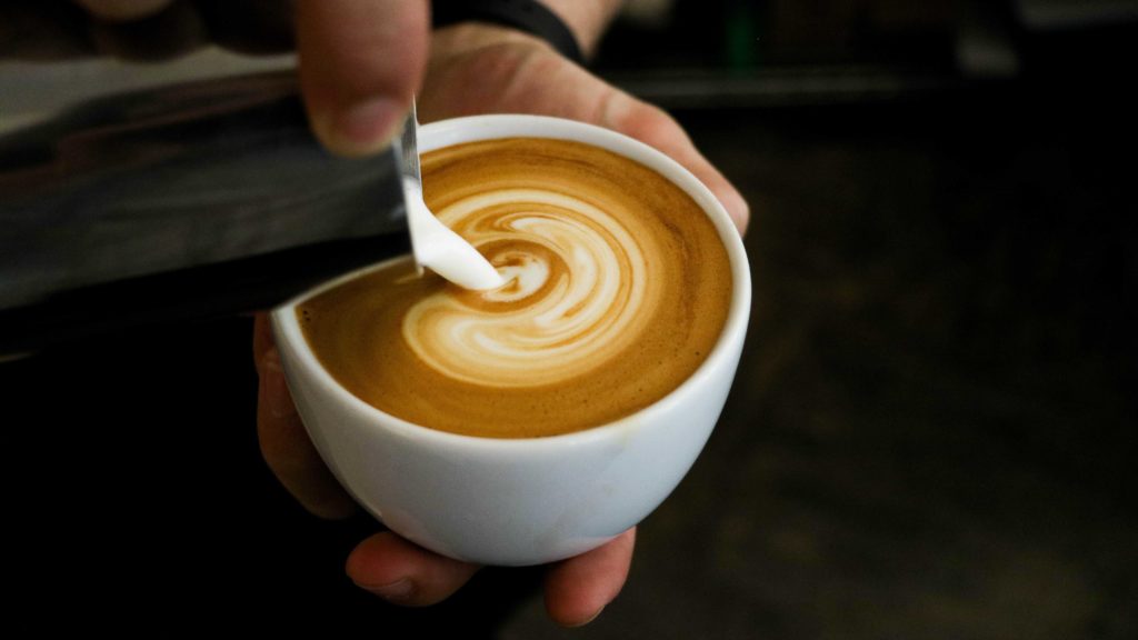 Pouring hot milk into a cup of coffee