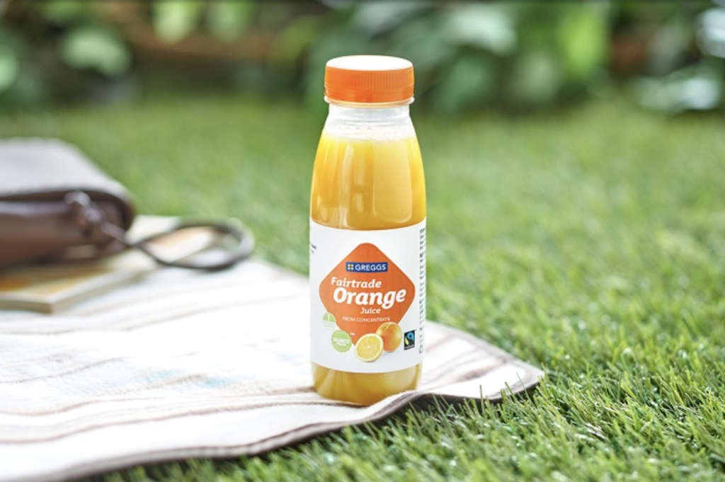 Greggs Fairtrade orange juice on a cloth on a mowed lawn
