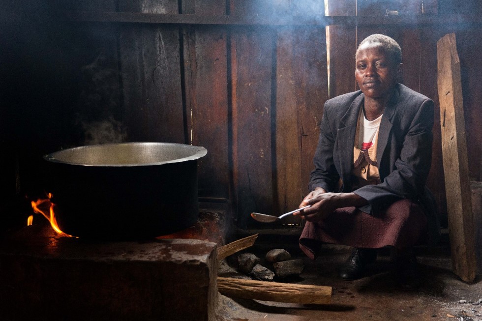 Growing Women in Coffee project - a woman in Kenya cooks over a wood fire