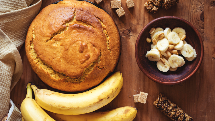 banana cake on a table with bananas, banana slices and sugar cubes