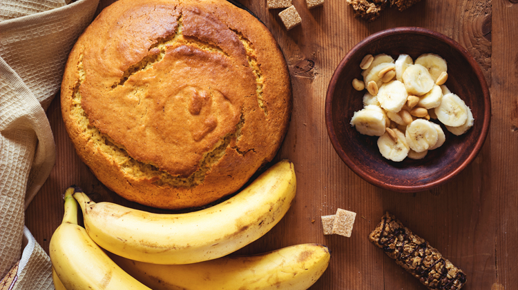 banana cake on a table with bananas, banana slices and sugar cubes