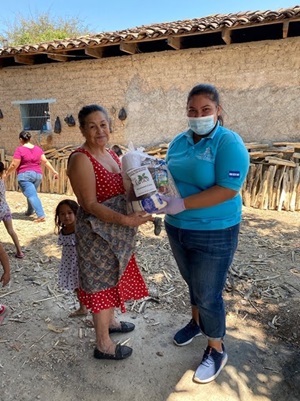 Member of CAFICO Fine Coffee co-op in Honduras hands a food and hygiene kit to a woman.