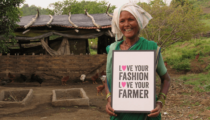 Lingu Bai Fairtrade Cotton Farmer and entrepreneur with 'love your fashion love your farmer' sign