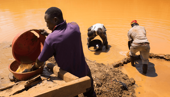 Miners working at a flooded opencast pit at the Busia United mine pan and wash for gold.