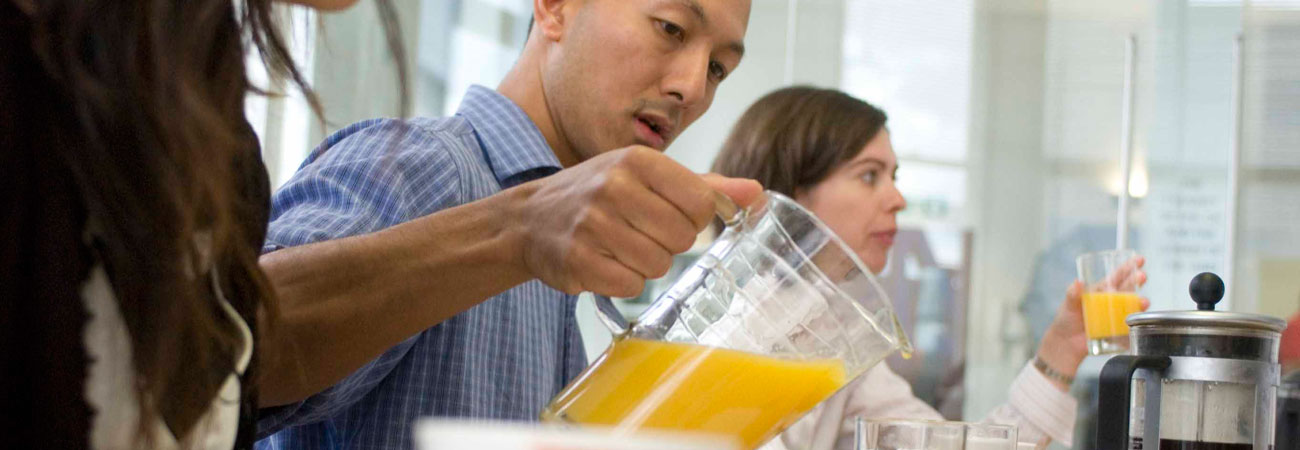 A man pours Fairtrade orange juice in the workplace