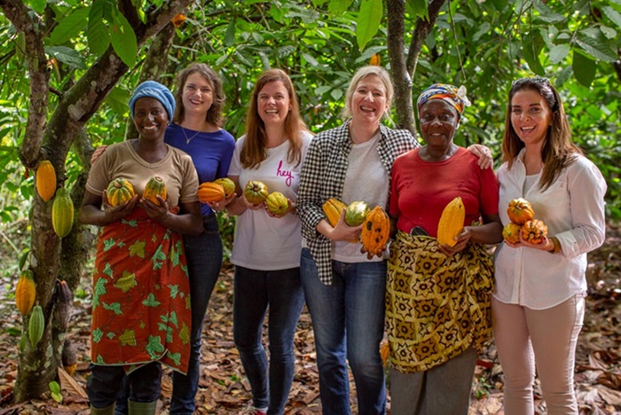 Staff from Co-op visit a cocoa farm in West Africa and are photographed here with two women cocoa farmers. They all cocoa pods