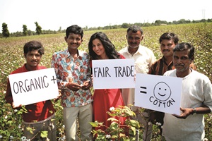 People Tree founder and CEO in a cotton field with cotton farmers, holding signs that say "organic + fair trade = cotton"