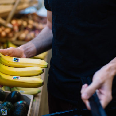 Shopper picks up Fairtrade bananas next to Fairtrade avocados