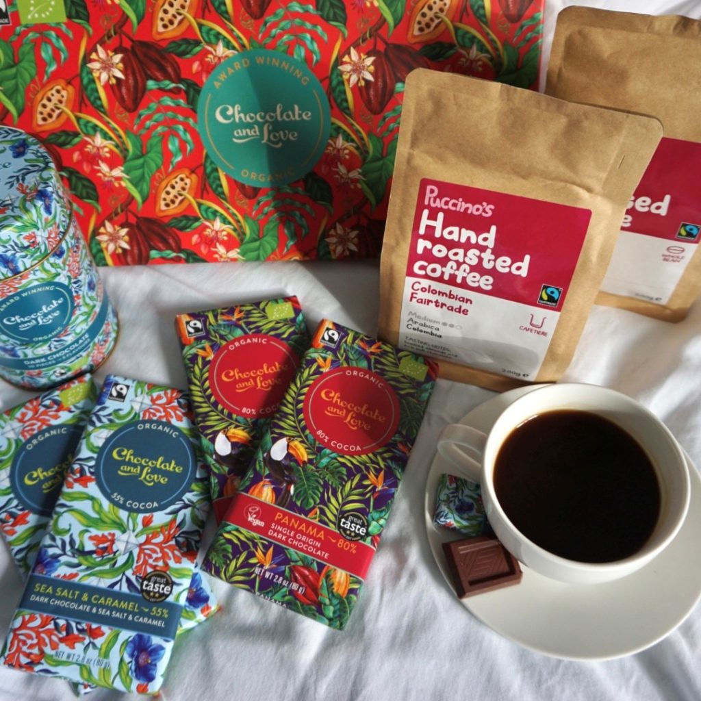 A selection of Chocolate and Love chocolates and a couple of bags of Puccino's coffee with a cup of black coffee.