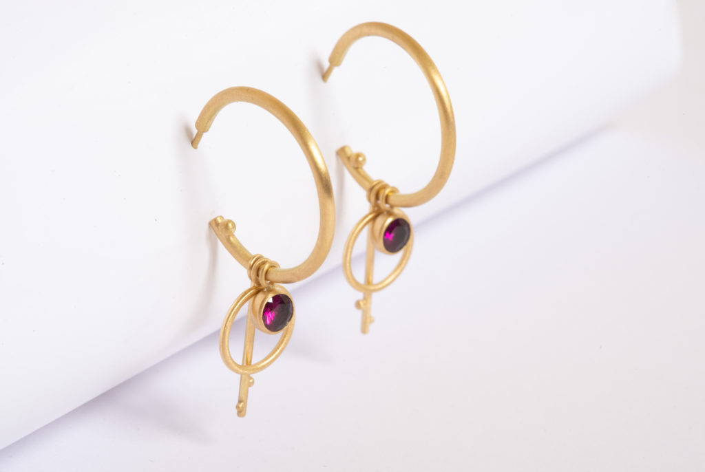 A pair of Fairtrade gold hoop earrings with pink jewel and gold decoration