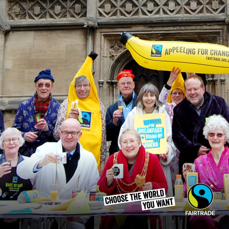 Fairtrade campaigners, dressed in pajamas and dressing gowns, and banana suits, drinking from Fairtrade mugs at a Fairtrade fundraising event in front of a church