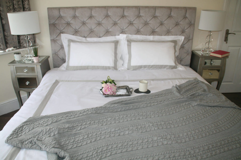 A bed made up with white and grey Fairtrade bedding