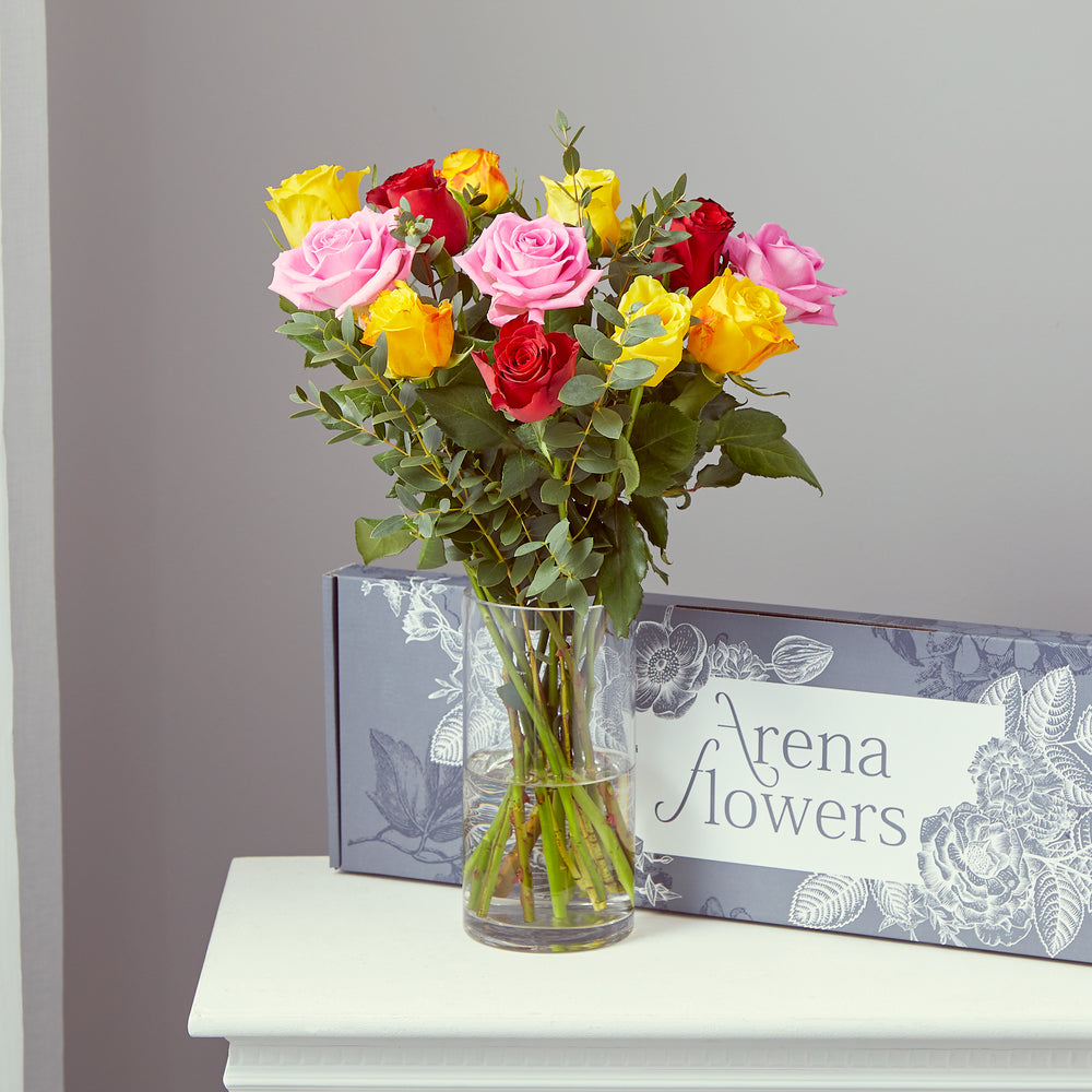 bouquet of pink red and yellow roses in a vase with an Arena Flowers box