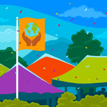Brightly coloured festival tents among tree tops, with a blue sky. Flags flying above the tents. Flag on the left has the Fairtrade Mark on a black background, middle flag shows a globe held between two hands on orange background, flag on the right shows a globe on a blue background.,