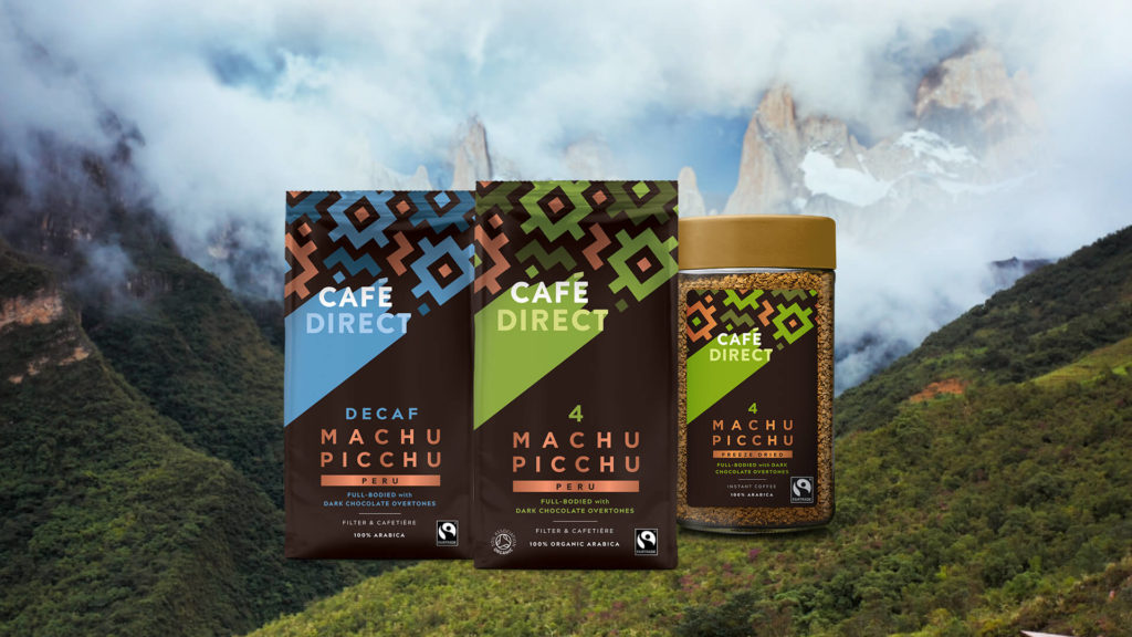 Cafe Direct Machu Picchu coffee, decaf coffee and freeze-dried coffee set on a background image of forested mountains with snowy tops