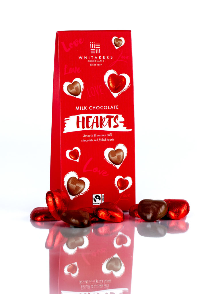 Whitakers Chocolate hearts package, with a scattering of red foil covered chocolates