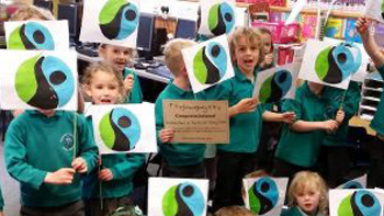 children holding hand made pictures of the fairtrade mark
