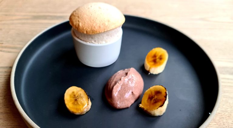 a plate with beautifully displayed banana souffle, brulee banana slices and vegan chocolate mousse