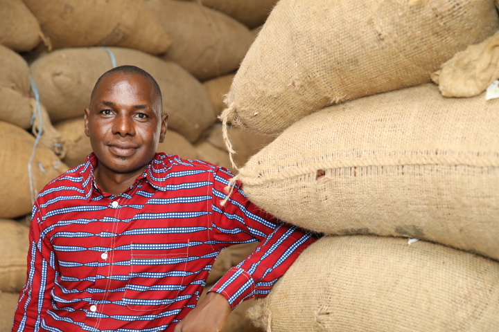 Bengaly Bourama portrait next to sacks of cocoa beans