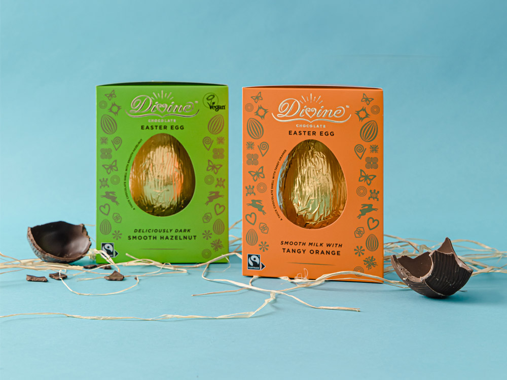 Divine Tangy Orange and Smooth Hazelnut eggs on a blue background with broken pieces of egg next to the egg boxes.