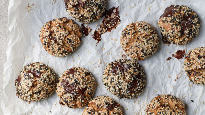 Tahini and chocolate chip cookies coated with sesame seeds on baking paper