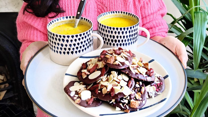 Chocolate Fruit and nut florentines on a plate with two mugs of ginger and turmeric tea