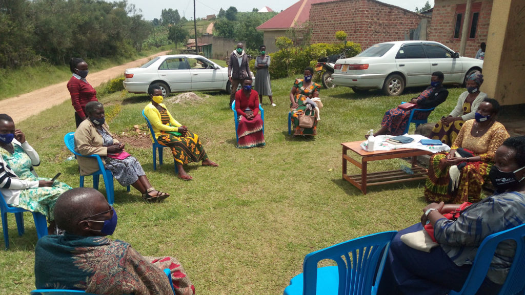 Women from ACPCU coffee co-operative speak to Fairtrade Foundation and Practical Action. They're sat in a circle of plastic chairs outside, wearing face masks