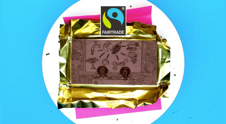 Chocolate bar carved with symbols representing Fairtrade - tap, tree, logo, corn, gender signs, plate with cutlery, money, two people sat on a bench looking at the symbols
