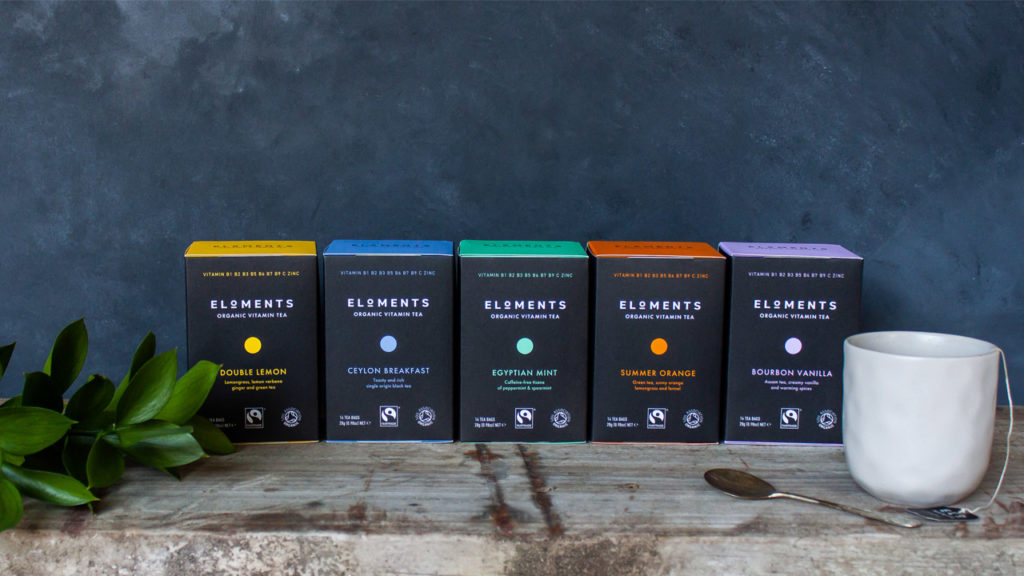 five types of Eloments tea lined up on a table with a mug of tea and a plant