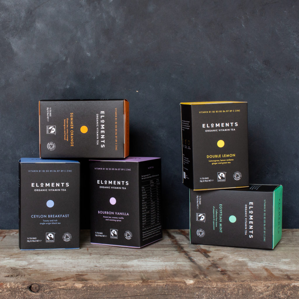Assortment of Eloments Teas on a wooden table, on a black textured background