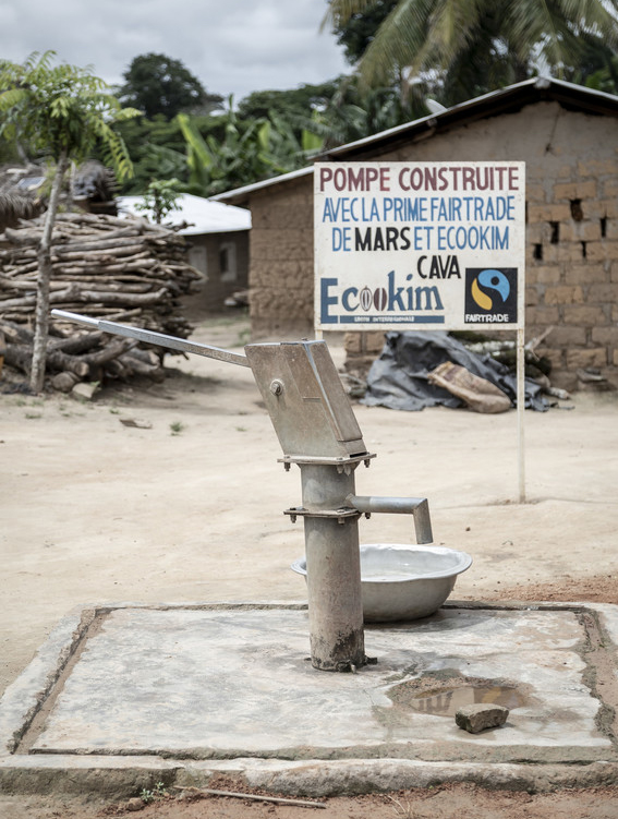 Water pump with sign in background saying that the pump was built by Ecookim, CAVA co-op and Fairtrade