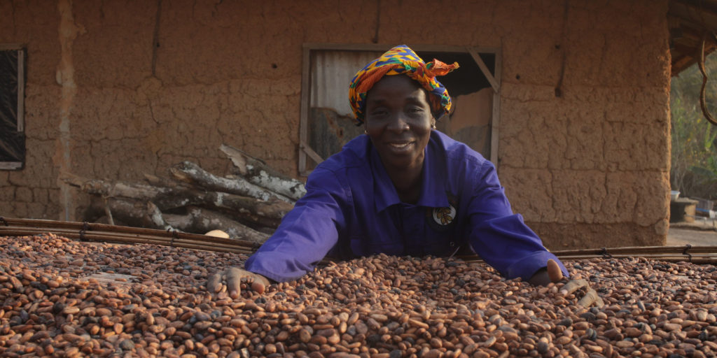 Portrait of Yaa Asantewaa leaning on a surface drying cocoa beans