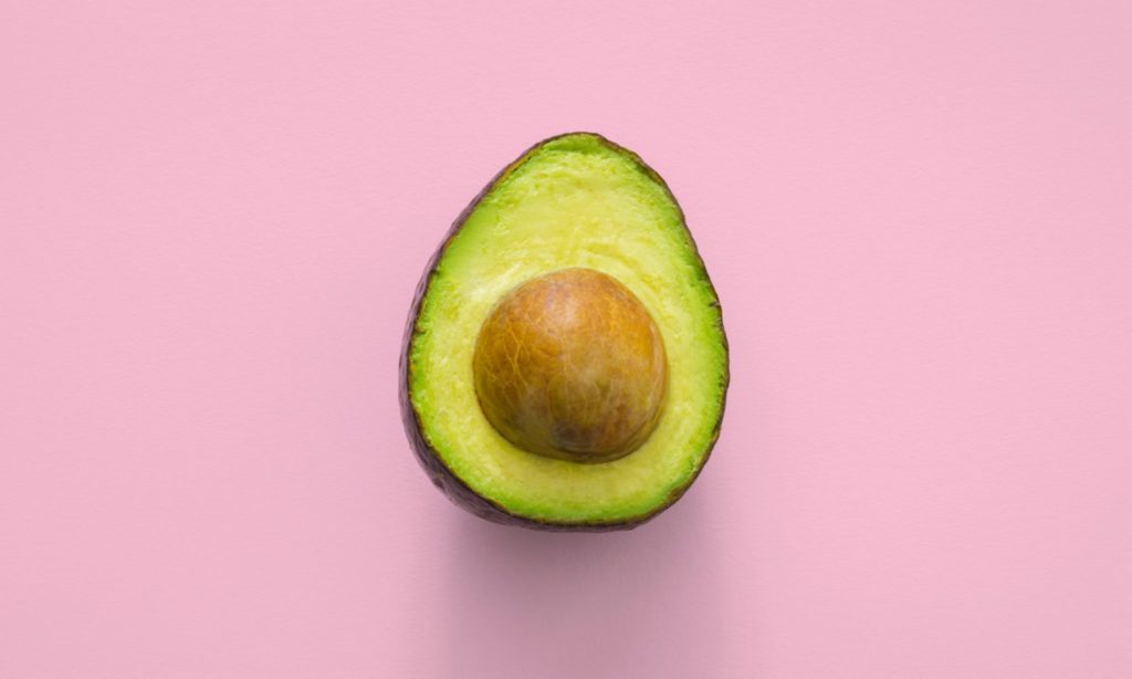An open avacado on a pink background