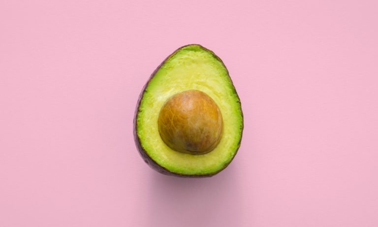 An open avacado on a pink background