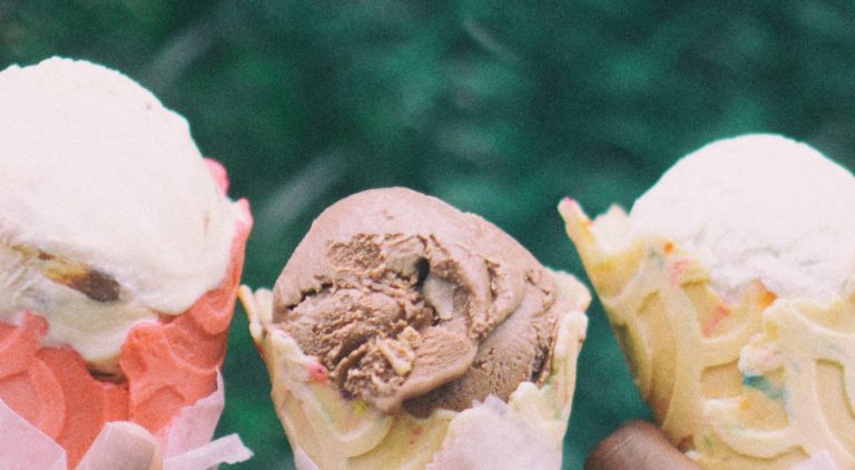 Three hands holding ice cream cones
