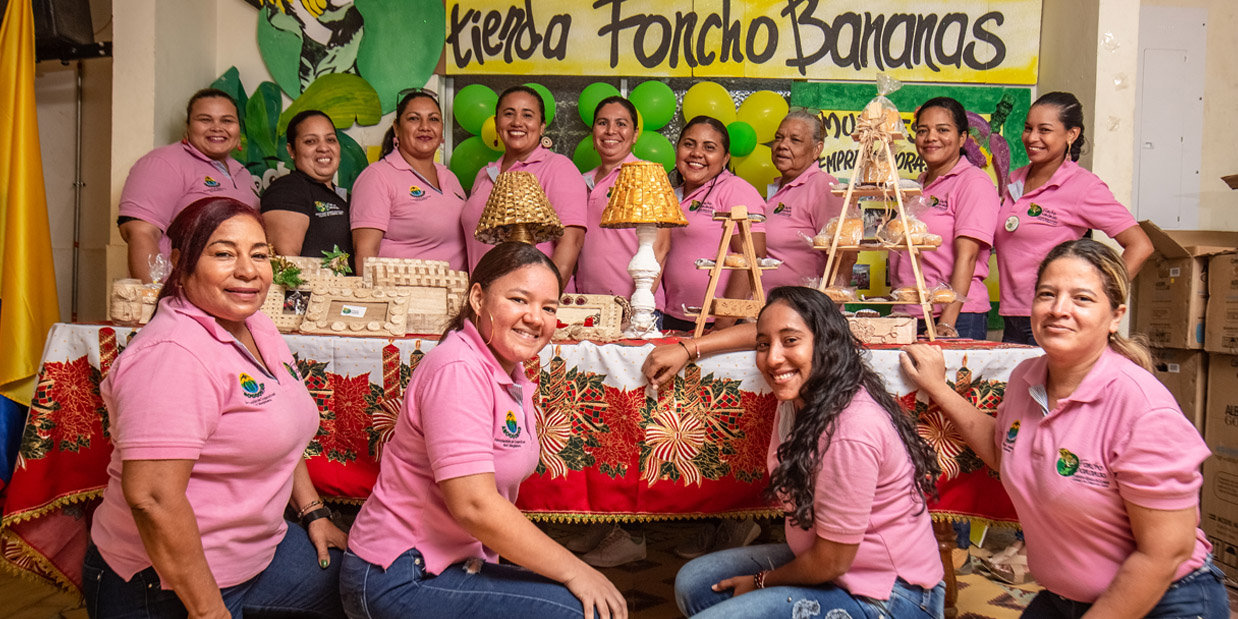 Portrait of Asocoomag women's group posing with a table of their banana products