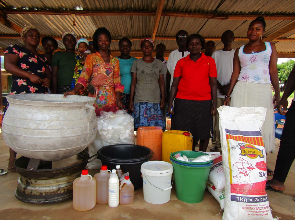 Women standing in front of soap making apparatus