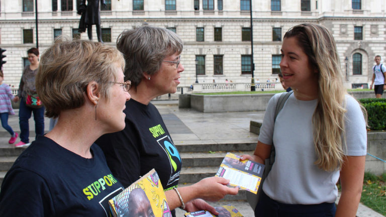Two Fairtrade campaigners hand a leaflet to a woman in London