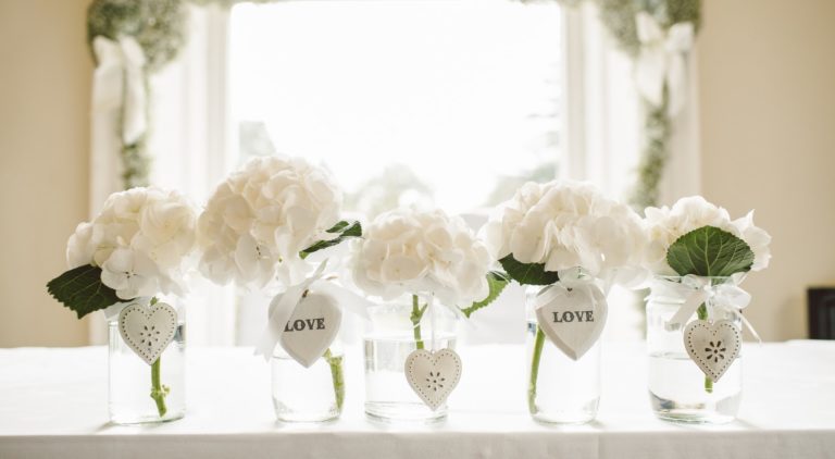 a display of white flowers in vases on a wedding table