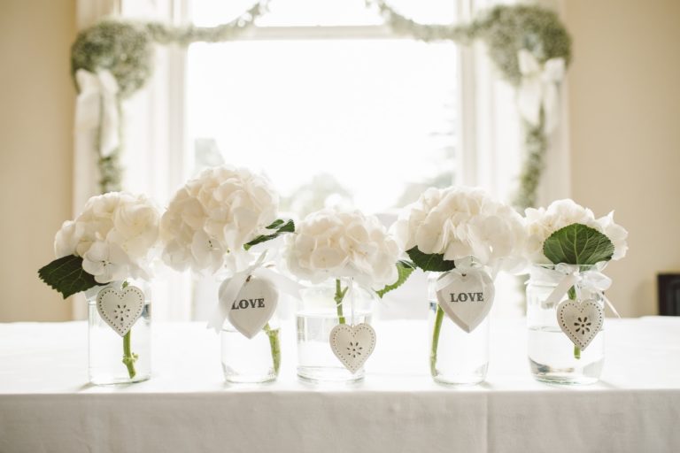 a display of white flowers in vases on a wedding table
