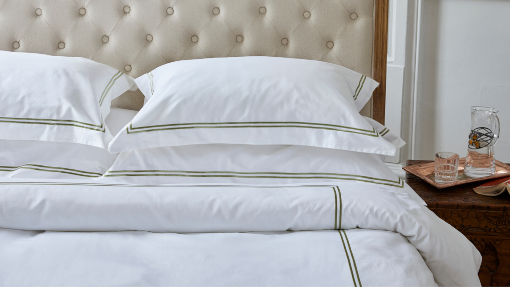 white bedding and pillows with green edging