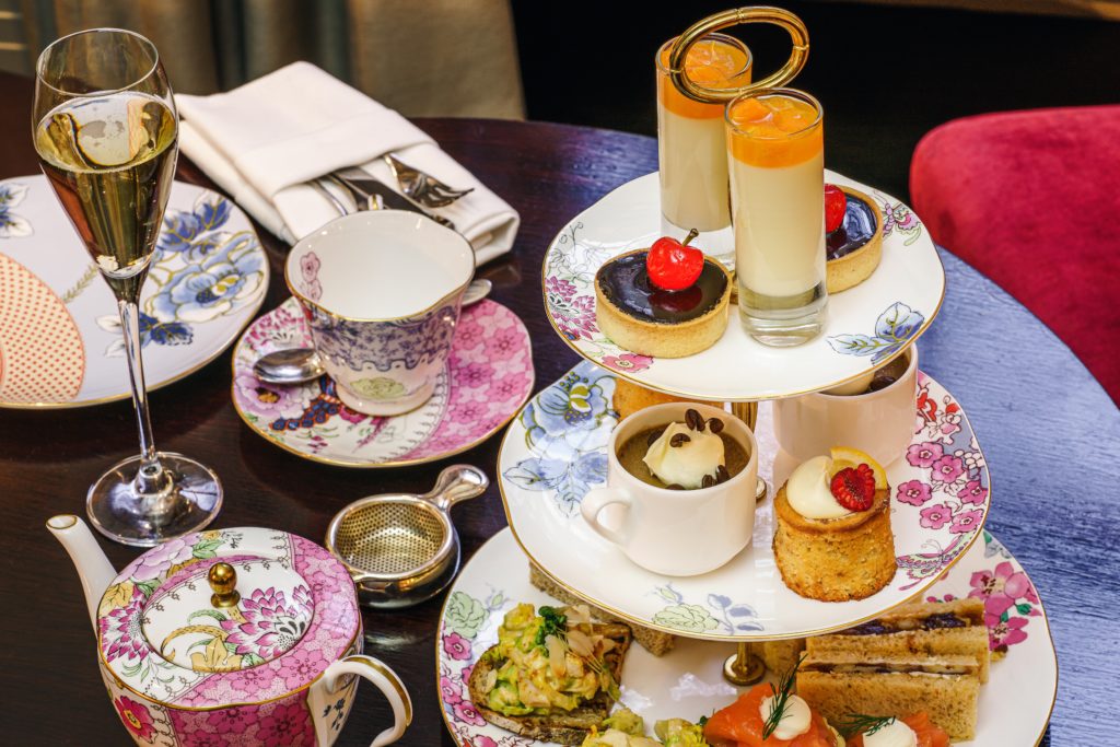 tiered cake stand with cakes, champagne flutes and tea cups on a table