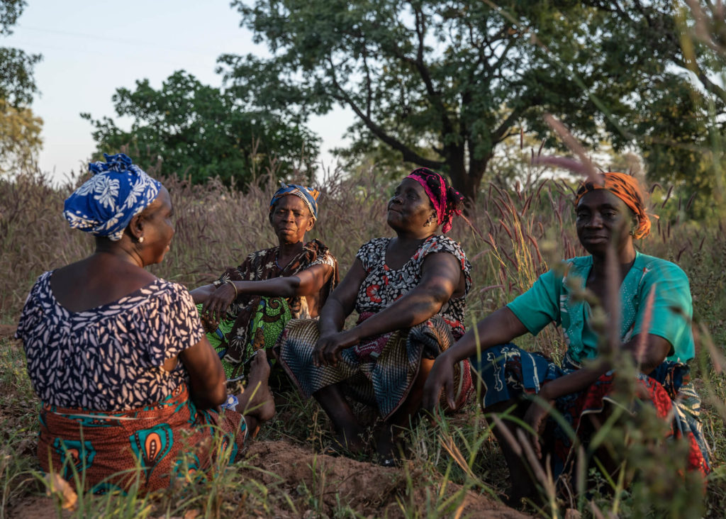 a group of women sitting on the ground in a field