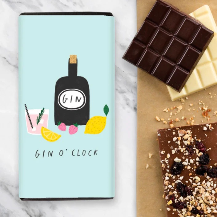 a bar of Quirky Chocolate Gin O'Clock with a selection of chocolate bars unwrapped next to it