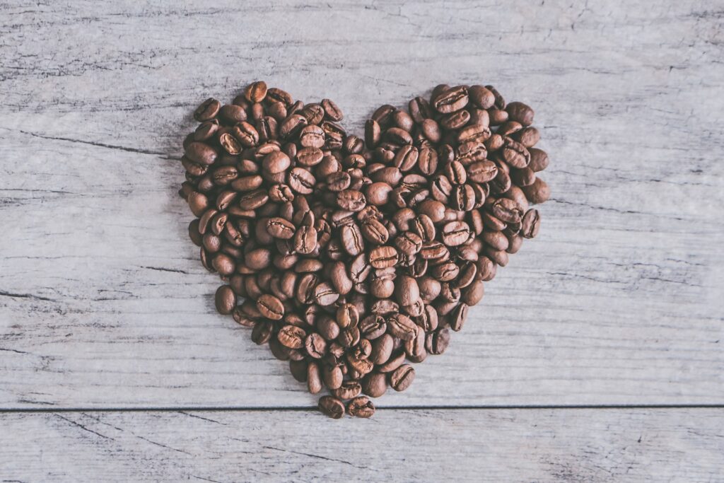 Coffee beans spread out in the shape of a heart on a grey table in the s